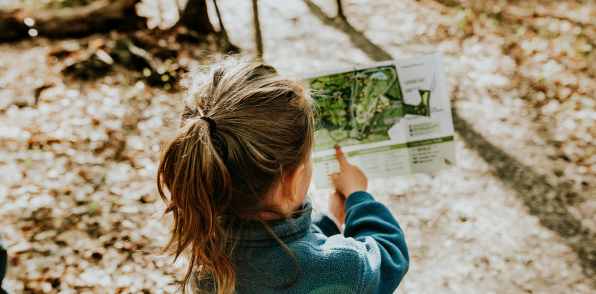 Girl looking for tree info in a park at Flats At 540 in Apex, North Carolina