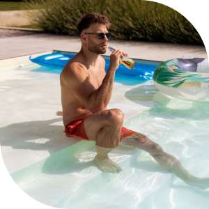 A man relaxing at the edge of a pool at Romero Apartments in Pensacola, Florida