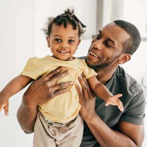 Resident holding up his smiling toddler at Dove Hollow Apartments in Allen, Texas