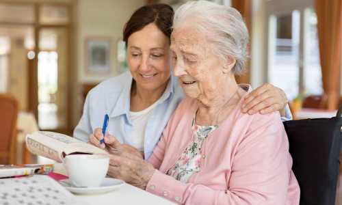 Nurse helping a resident her crossword puzzle at The Barclay in Charlottesville, Virginia