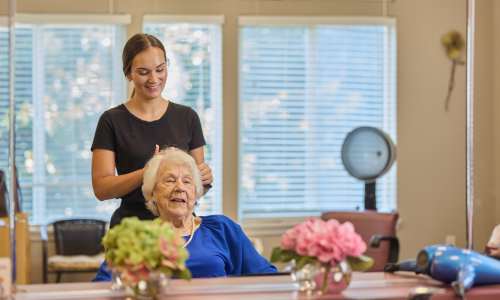 Woman styling hair for elderly woman in bright salon at Barclay House of Oakleaf Village in Lexington, South Carolina