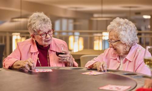 Two elderly women enjoying a card game at a round table at Barclay House of Oakleaf Village in Lexington, South Carolina
