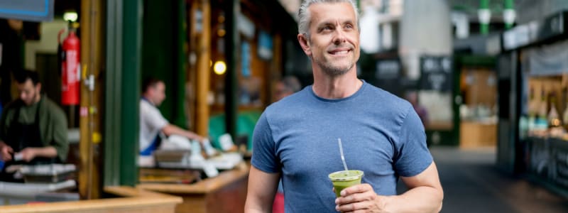 Man walking down the street enjoying his cold iced coffee near Eastgold Long Island in Long Beach, New York