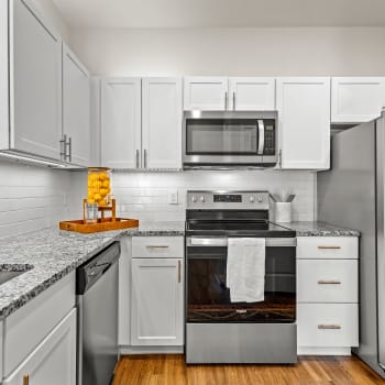 Upgraded stainless steel appliances and white cabinets in an apartment kitchen at Cypress Creek at River Oaks Boulevard in Waxahachie, Texas