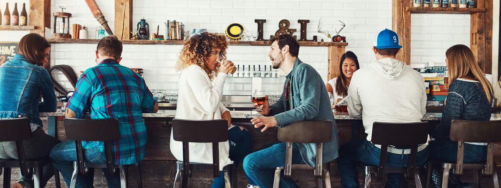 A couple discusses something over drinks at a local bar near Hawthorne Hill Apartments in Thornton, Colorado