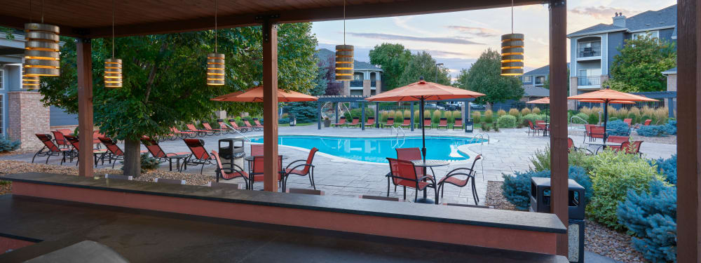 Poolside tables and chairs on a beautiful evening at Hawthorne Hill Apartments in Thornton, Colorado