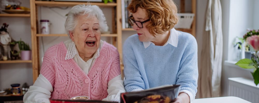 Two residents looking through a photo album at The Ridge at Lansing in Lansing, Michigan