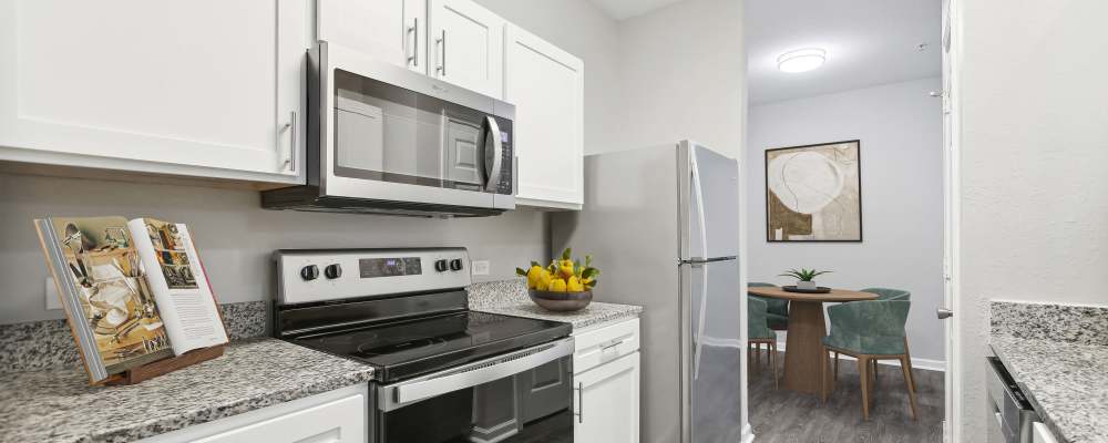 Modern kitchen with wooden cabinets, stainless-steel appliances and granite countertops at The Haven At West Melbourne in West Melbourne, Florida