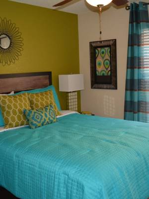 Spacious bedroom with a wood headboard,a nightstand, and a large window at The Abbey At Northlake in Riviera Beach, Florida