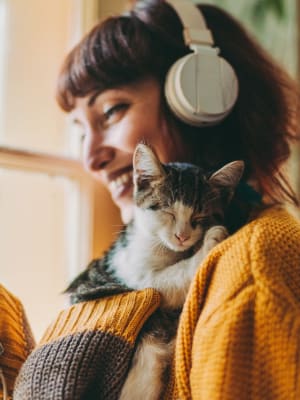 Resident enjoying music in her apartment and cuddling her cat at Creekside at Kenney's Fort in Round Rock, Texas