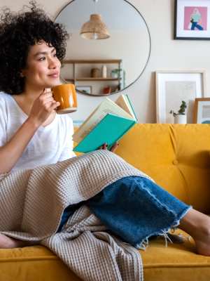 Resident having her morning coffee on the sofa at The Abbey at Sonterra in San Antonio, Texas