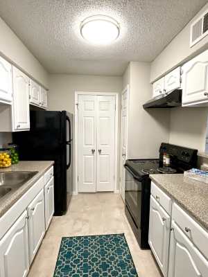 Galley-style kitchen with faux granite countertops at The Abbey at Medical Center in San Antonio, Texas