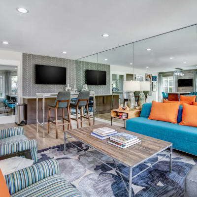 Large community clubhouse with lounge seating and multiple flat screen TVs at Sofi at Los Gatos Creek in San Jose, California