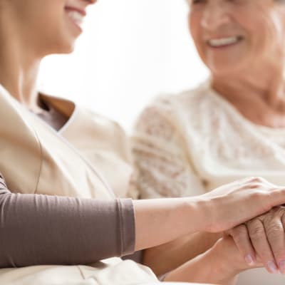 Resident smiling and holding hands with on-site nurse at Westminster Memory Care in Aiken, South Carolina