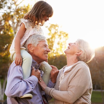 Grandparents playing with their granddaughter outdoors at Westminster Memory Care in Aiken, South Carolina