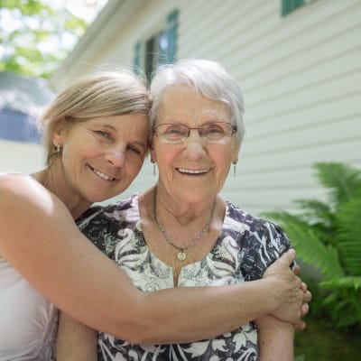 Caretaker hugging a resident outside at Deephaven Woods in Deephaven, Minnesota