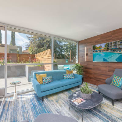 Lounge area with a couch and large windows looking out to the pool area at Mia in Palo Alto, California