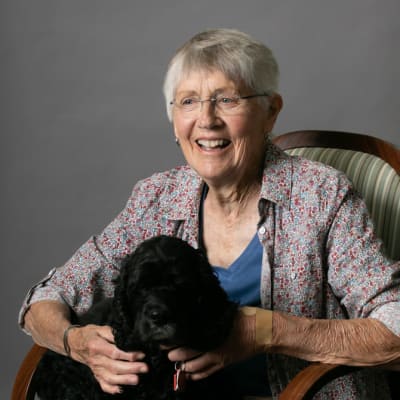 Resident sitting in a chair with her cute black dog at Deephaven Woods in Deephaven, Minnesota