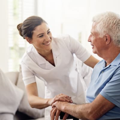 Caretaker talking to a seated resident at York Gardens in Edina, Minnesota