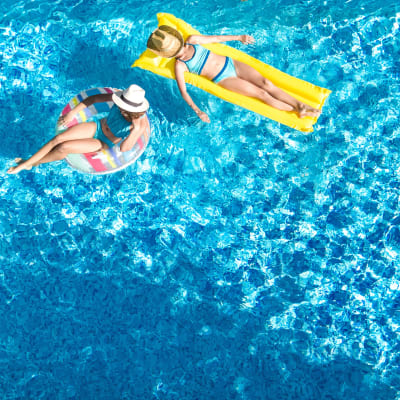 Two residents floating pool on pool raft and innertube at Marq on Burnet in Austin, Texas
