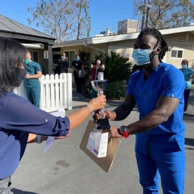 Staff nurse handing a resident a small bag at Huntington Terrace in Huntington Beach, California