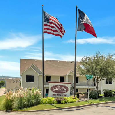 Entrance to a Monticello Asset Management community with large American and Texan flags in Dallas, Texas