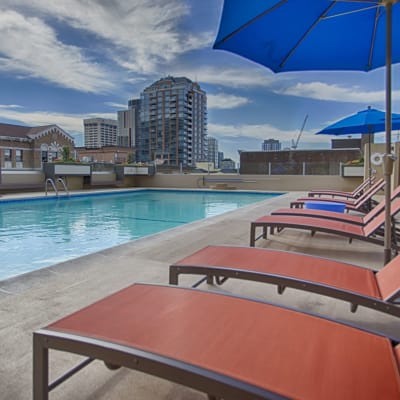 Large swimming pool with comfortable lounge chairs on a sunny day at Panorama Apartments in Seattle, Washington