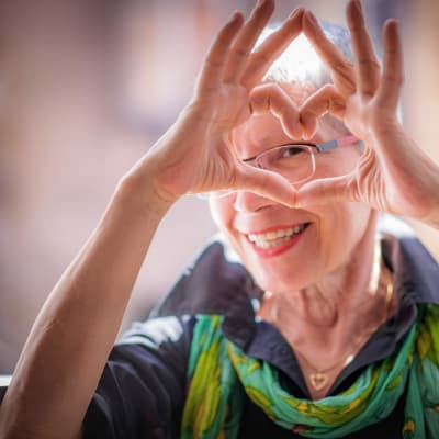 Resident making a heart symbol and smiling at Towerlight in St. Louis Park, Minnesota. 