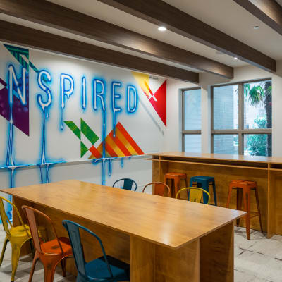 Resident bar with wooden tables and multicolored metal chairs at Bellrock Summer Street in Houston, Texas