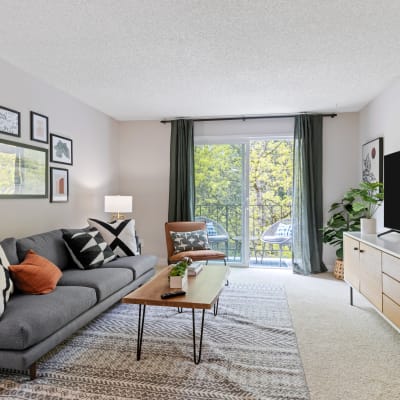 Large living room with good natural light coming from a sliding-glass door leading to a balcony in a model home at Haven Apartment Homes in Kent, Washington