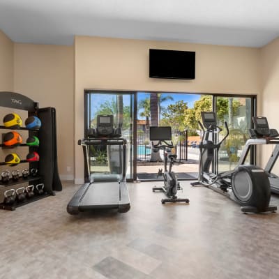 Updated fitness center with various exercise equipment and a view of the pool at Terra Camarillo in Camarillo, California