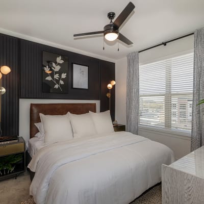 Bedroom with ceiling fan and bed with white comforter at Auro Crossing in Austin, Texas