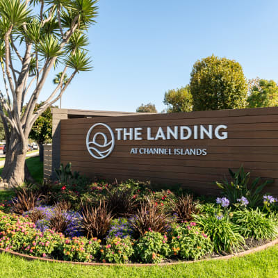 Monument sign welcoming residents to their new homes with pet-friendly greenery at The Landing at Channel Islands in Oxnard, California