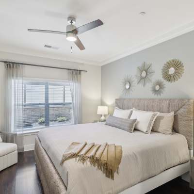 Model bedroom with ceiling fan and wood-style flooring at Somerset in McDonough, Georgia