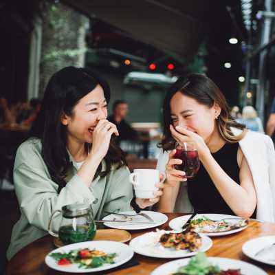 Two women sharing a laugh while having a meal near The Canopy Apartment Villas in Orlando, Florida