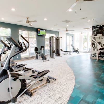 Community fitness room with large windows at Station 3700 in Euless, Texas