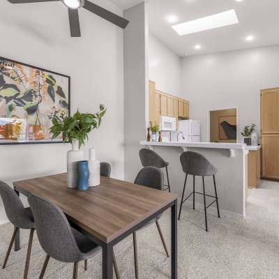 Dining area with an accent wall looking over the breakfast bar into the kitchen of a model home at Sofi Canyon Hills in San Diego, California