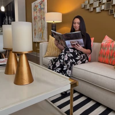 Apartment Resident Sitting on a Sofa and Reading a Magazine in a Living Room at Anthem Cityline in Richardson, Texas