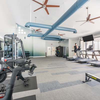 Spacious fitness center with various workout equipment and machines, including treadmills, ellipticals, stationary bikes, and punching bags for residents to use at Veranda La Jolla in San Diego, California