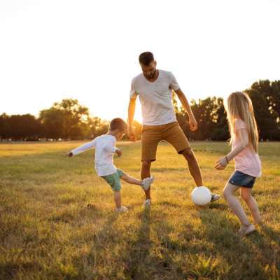 Man playing soccer with two children in field at Ashley Oaks in Charleston, South Carolina