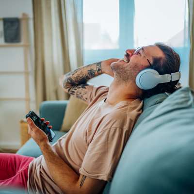 Man with tattoos wearing headphones on couch at The Heights at Materra in Baton Rouge, Louisiana