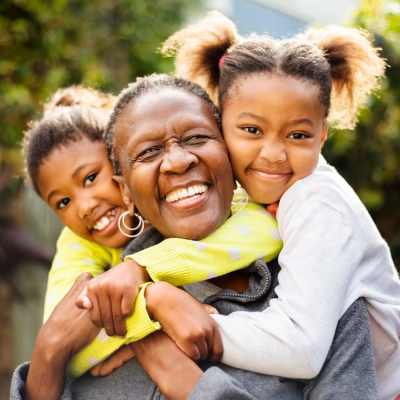 Smiling grandmother with two girls outdoors at Valley Brook Townhomes in Rochester, New York