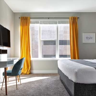 Yellow curtains and gray bed with desk at 223 E Town in Columbus, Ohio