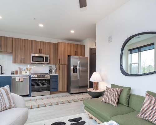 Modern model unit with brown cabinetry and kitchen counters, wood flooring and large windows at The Row in Raleigh,North Carolina