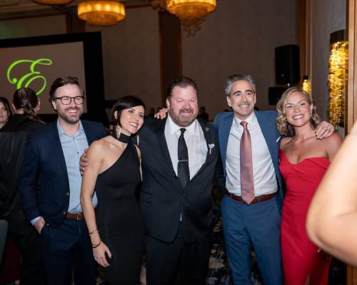 Group dressed in formal attire posing together at an indoor event with warm lighting and a screen in the background at Pillar Properties in Seattle, Washington
