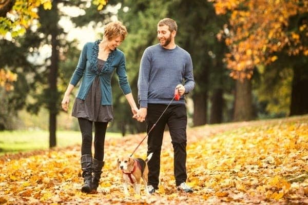 A couple smiles at they walk their dog near Spice Tree Apartments