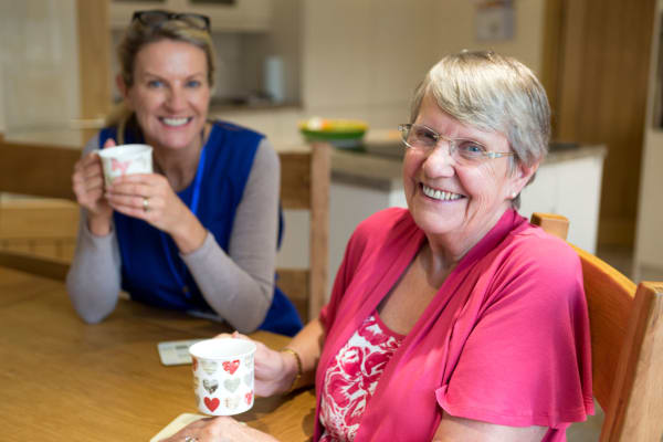 A resident sharing a cup of coffee with a caretaker at Regency Park Senior Living, Inc.