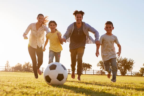 Family playing soccer in a field near Heatherwood Apartments in Sacramento, CA