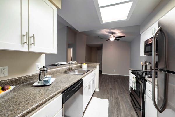 White renovated kitchen with Stainless steel appliances at Sierra Del Oro Apartments in Corona