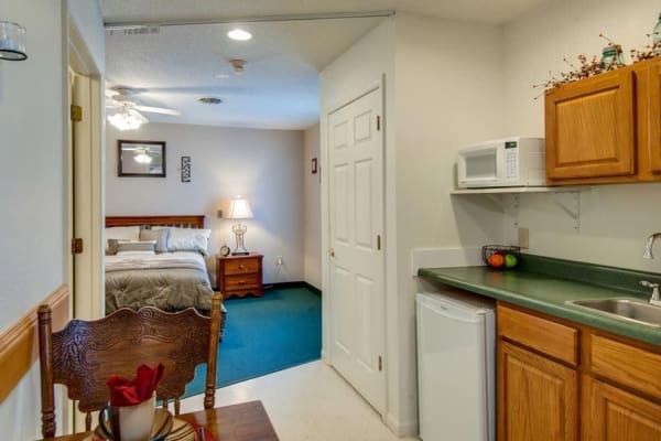 Assisted living apartment kitchen facing the bedroom at Victorian Place of St. Clair in Saint Clair, Missouri